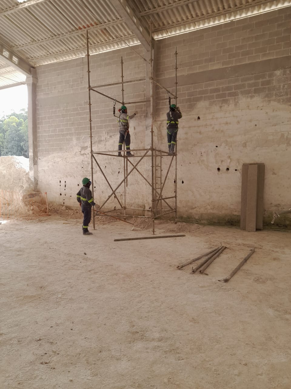 Equipe em andaime dentro do galpão industrial