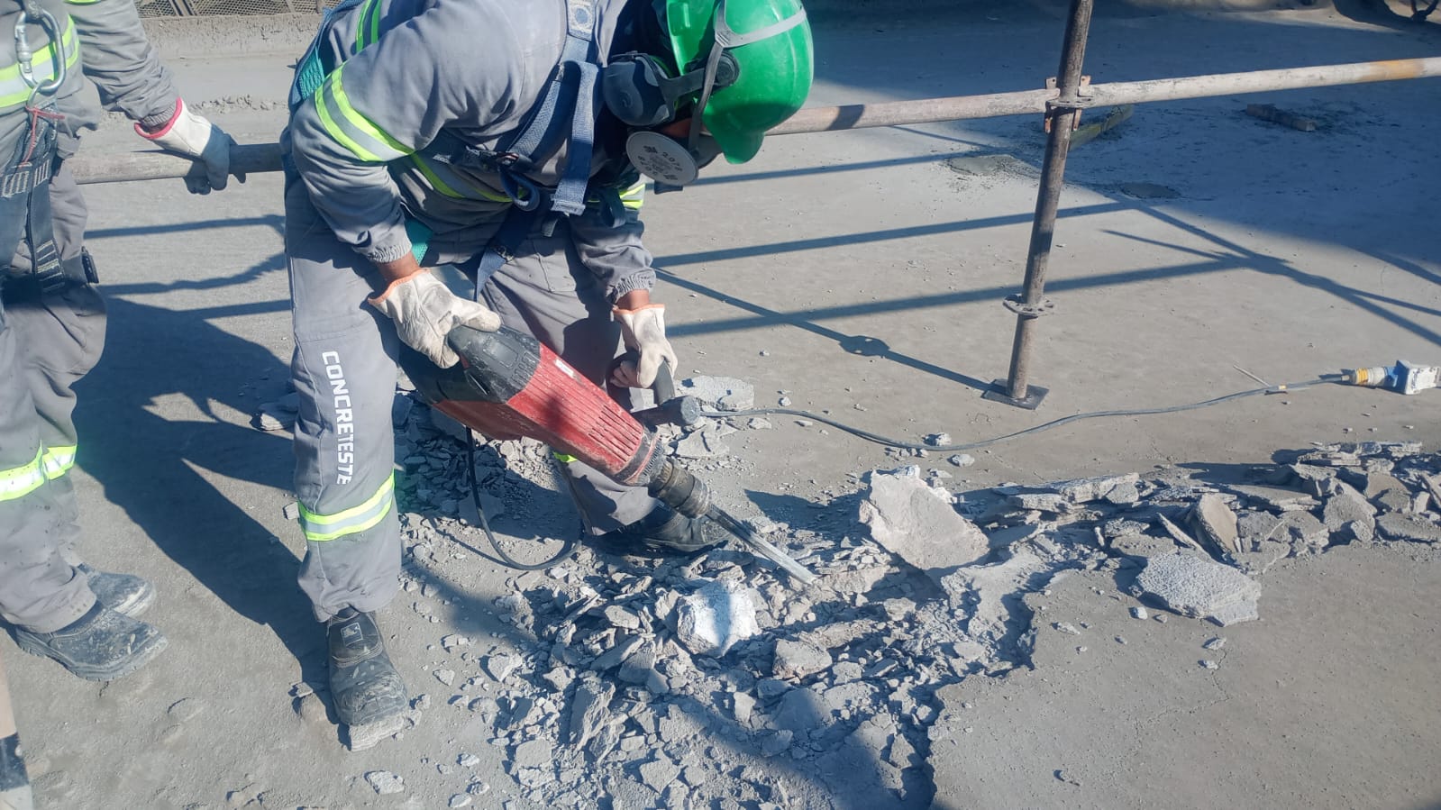 Profissional utilizando ferramenta de demolição em área de concreto