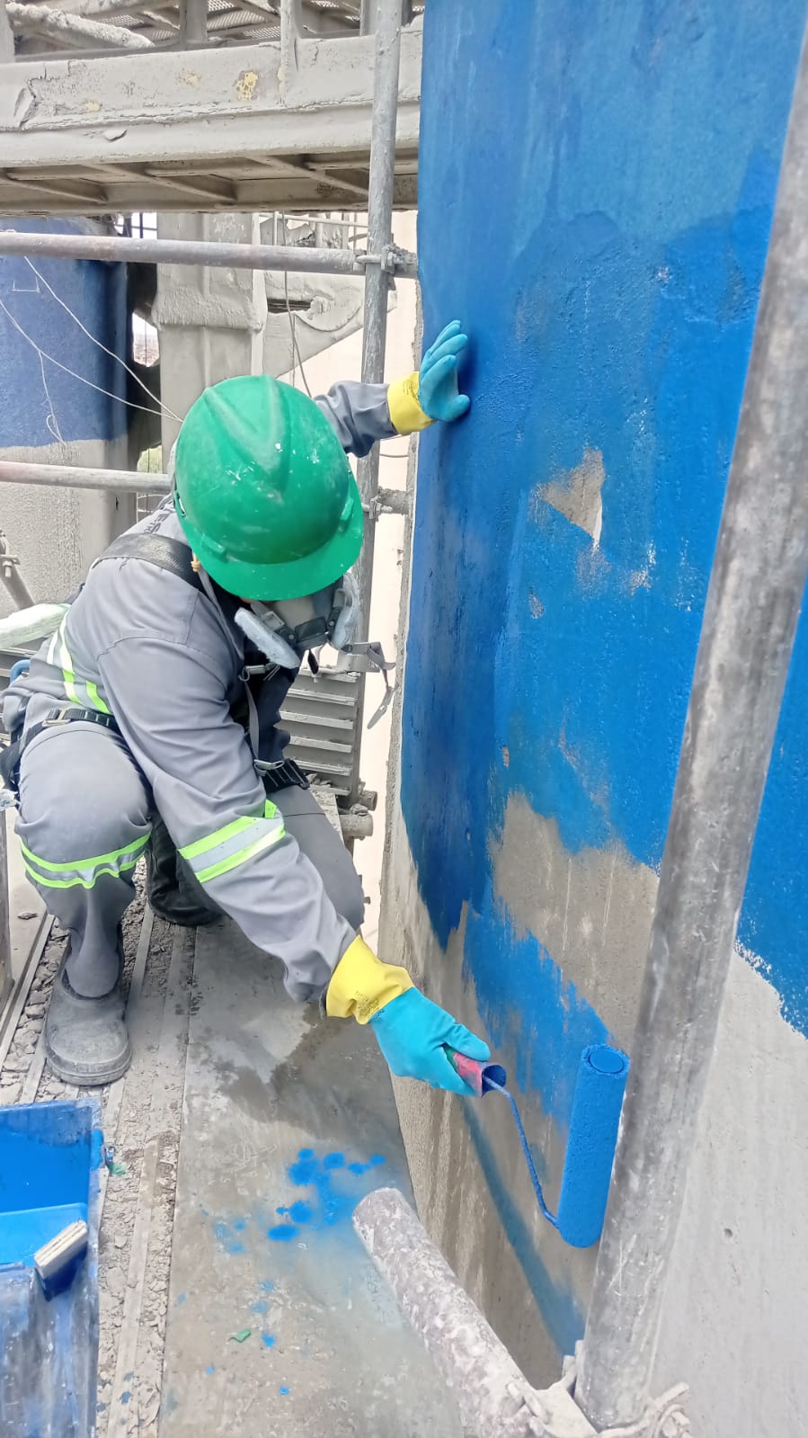 Profissional aplicando revestimento azul na superfície do silo